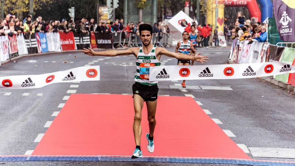 Corredor cruzando la meta como parte de planes de entrenamiento para correr más rápido y mejorar en 5K.