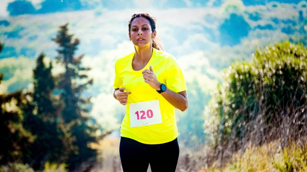 Mujer en ruta de montaña durante planes de entrenamiento para correr un maratón completo.