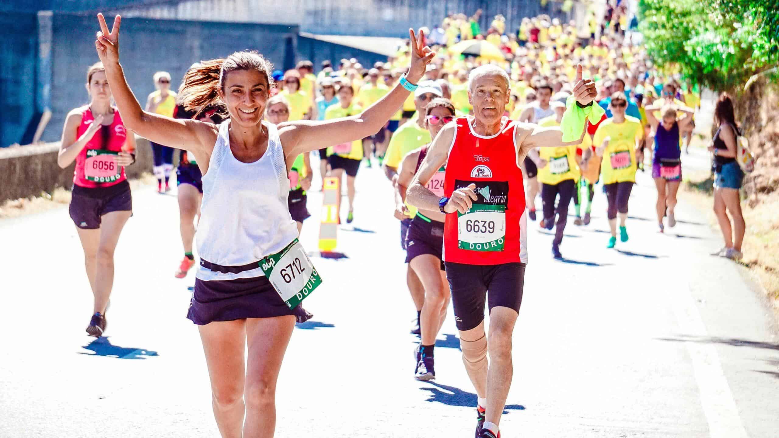 Mujer cruzando la meta con los brazos en alto, celebrando su logro en una carrera popular.