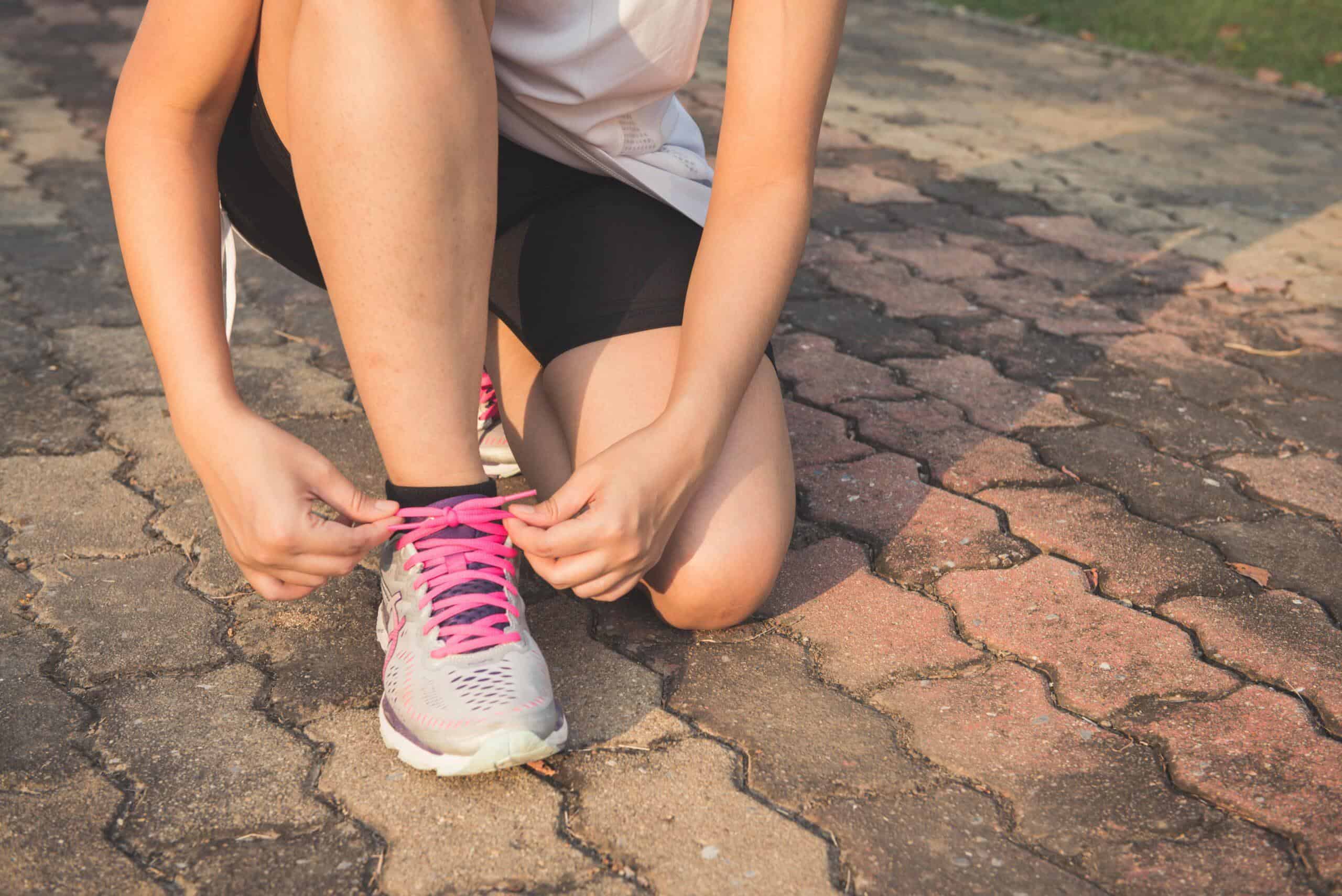 Persona atándose las zapatillas antes de un entrenamiento, preparándose para empezar a correr y disfrutar cada paso.